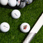 titleist trufeel golf balls next to the handle of a golf club on green grass